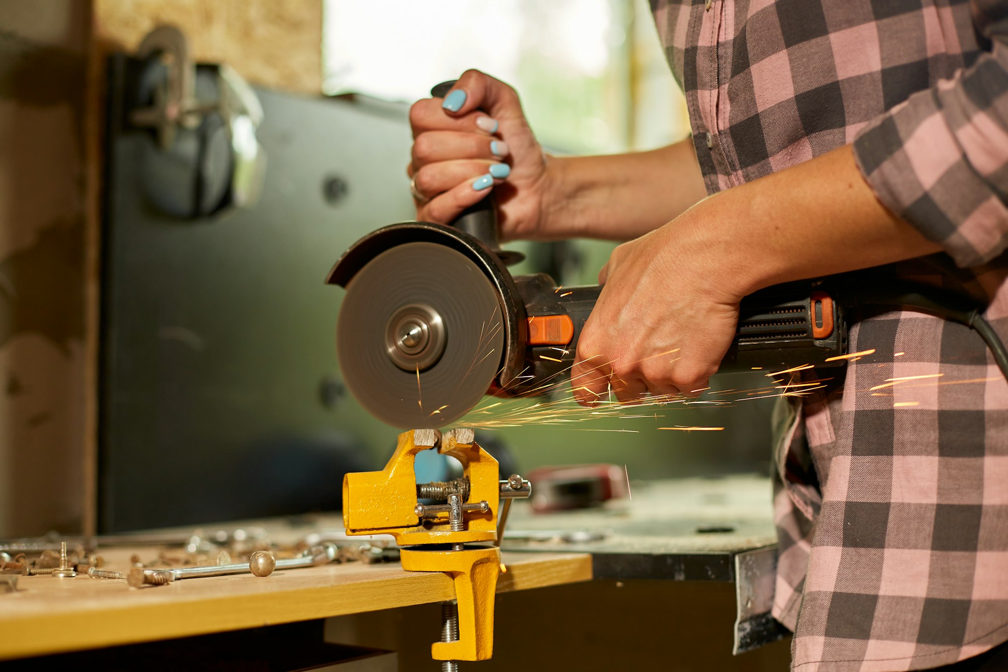 Woman locksmith works with grinder machine, fly bright sparks